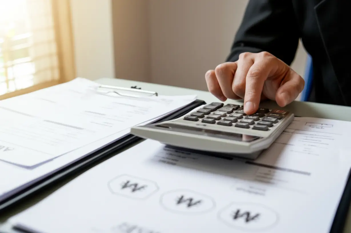 Calculator-showing-Korean-Won-figures-next-to-icons-for-income-and-assets,-depicting-the-income-recognition-calculation.