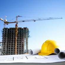 Realistic-view-of-new-apartments-being-built,-foreground-showing-blueprints-and-a-hard-hat-indicating-the-planning-phase-of-a-housing-cooperative.