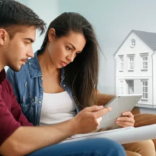 A-young-couple-reviewing-property-options-on-a-tablet,-contemplating-their-first-home-purchase-decisions.