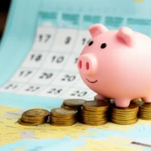 Cute-piggy-bank-on-coin-stack-looking-at-world-map-with-calendar,-representing-overseas-dividend-income