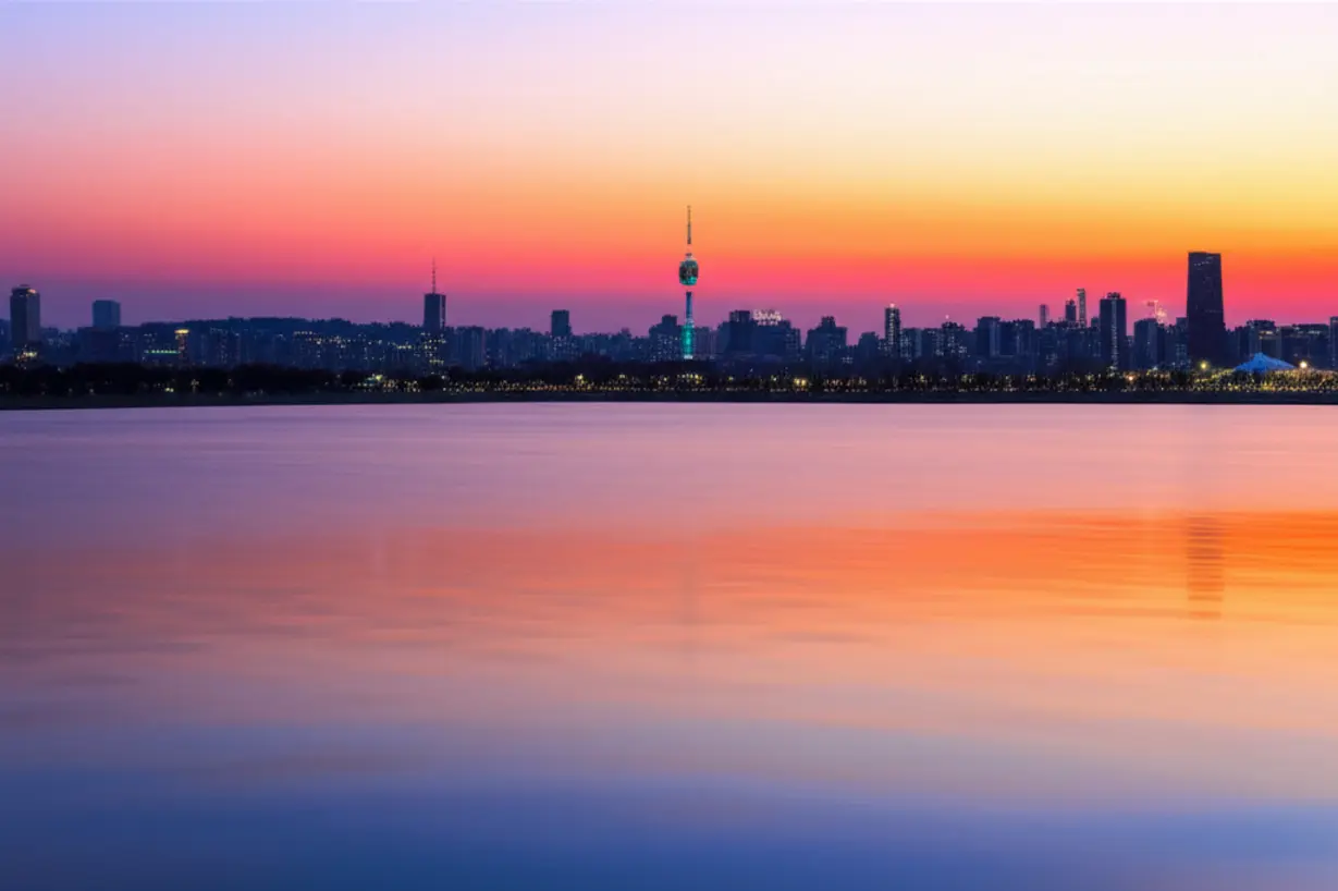 아름다운-석양이-물드는-잠실-한강공원-물놀이장과-멀리-보이는-롯데월드타워의-야경.-시원한-물놀이와-함께-환상적인-경치를-즐길-수-있는-순간을-표현합니다.